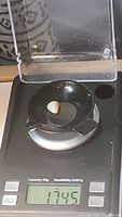 Photo of the opal gemstone being weighed on a digital jewelry scale showing 1.745 grams (approximately 1.75 carats).