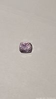 Photo showing the cushion cut pink kunzite gemstone with visible ice-like inclusions on a neutral background.