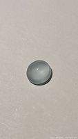 Top-down image of the translucent sky blue aquamarine cabochon on a neutral background, showing color and surface texture.