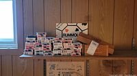 Shelf with stacked playing card decks, two Rummoli board game boxes, and wooden cribbage boards on the right side.