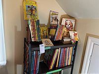 Two shelves filled with various children's books, including vintage illustrated books and Disney Adventures magazines arranged in stacks.