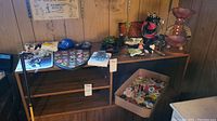 Wide view showing table with multiple collectible items including pins, wood decor, and figurines.