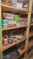 Wooden shelving unit with assorted plastic food storage containers with lids in various colors and sizes, stacked and grouped on the shelves; includes white, blue, green, and orange containers.