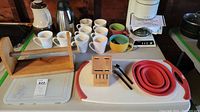 Coffee carafe, ceramic mugs, wooden mug holder stand, silicone collapsible trays, plastic trays.