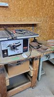 Shopcraft table saw on wooden table with sanding disks visible to the right and additional table surface at the back.