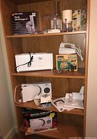 Full shelf view showing all appliances with boxes: Black & Decker chopper, Iona mixer box with mixer, Proctor Silex toaster, Salton slicer.