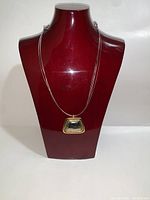 Full view of necklace displayed on bust showing multi-strand chain and pendant