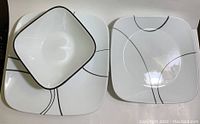 Photo of stack of dinner plates, lunch plates, and one bowl showing square shape and black line design.