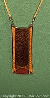 Close-up front view of the rectangular pendant necklace on green background.