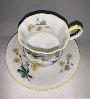 Top view of teacup showing scalloped rim, yellow flower decoration inside and outside, and yellow rim detail
