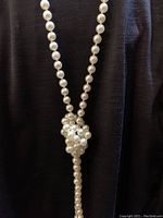 Necklace worn in a lariat knot style hanging down against black background