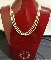 3-strand freshwater pearl necklace displayed on red bust.
