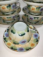 Stacked teacups and saucers highlighting the floral hand painted design and eggshell porcelain material.