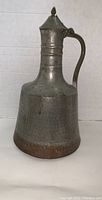 Front view of the large hand hammered copper ewer showing shape, handle, and lid.