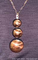 Close-up of the three circular copper pendants showing their reflective surface and smooth finish.