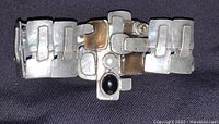 Front view of chunky pewter bracelet on black surface showing linked geometric shapes with black and white stones set and slight patina.