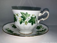 Side view of Queen Anne bone china teacup showing green grapevine leaf pattern, gold trim on rim and handle, no chips or cracks visible