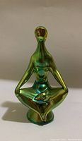 Front angle view of green eosin metallic glazed seated porcelain figurine with bowl in lap