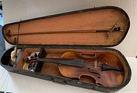 Full view of violin with the bow, placed inside the open wooden case.
