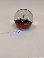 Front view of the aquarium style fish glass paperweight showing clear glass dome, red base, and two miniature fish inside.
