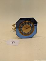Front view of the Art Deco blue mirror electric clock with round gold and blue face and octagonal frame.