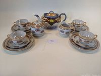 Full view of assembled tea service for four including teapot, sugar bowl, creamer, cups, and saucers.