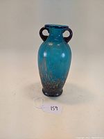 Front view of blue glass vase with loop handles and gold flake decoration on base