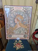 Full view of the framed reproduction print depicting a female profile with decorative Art Nouveau motifs and zodiac symbols, set in a purple frame with glass.