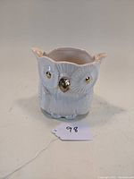 Front angled view of a white ceramic owl planter with gold eyes and beak showing scalloped top opening and feather detailing.