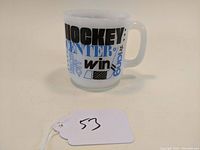 Photo showing front and side of milk glass mug with hockey-themed blue and black print.
