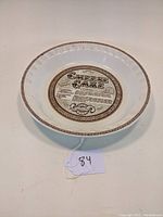 Ceramic pie plate shown from an angle highlighting the cheesecake recipe print and decorative border.