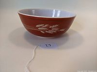 Side view of the vintage Pyrex mixing bowl showing the rust-orange color and white wheat stalk pattern of the Autumn Harvest design.