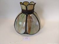 Side view of vintage slag glass lamp shade showing curved glass panels and decorative metal framework with scalloped top edge.