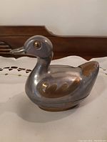 Side view of brass and silver duck trinket dish showing detailed brass accents on wings, beak, and eyes.