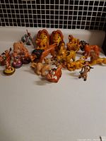 Photo showing the full lot of Lion King figures arranged on a white surface, all characters visible with some duplications visible.