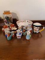 Full lot arranged on table showing all ceramic pieces including vases, bowl, salt and pepper shakers, and Toby jugs.
