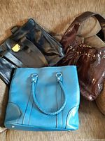 Three shoulder bags in used condition: black Nina Ricci bag, brown textured bag, blue tote with braided handles