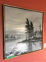 View of the entire framed painting hung on a red wall showing the lakeside landscape scene with windswept trees and water