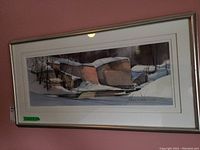 Full view of framed winter landscape print with snow-covered rocks and trees, in metallic frame.