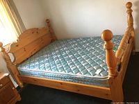 Full view of queen size four poster wooden bed with mattress on it.