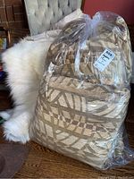 Packaged set of cushions and throw in clear plastic bag showing geometric pattern fabric.