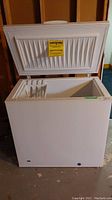 Frigidaire chest freezer with lid open showing exterior and interior dimensions.