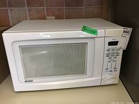 Front view of white Kenmore microwave oven showing door and control panel with buttons and dial.