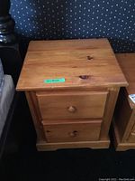 Full view of one wooden nightstand showing the top surface and front with two drawers and round wooden knobs.