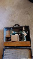 Vintage Viking sewing machine stored in metal case with patterned blue interior lining and black handle.
