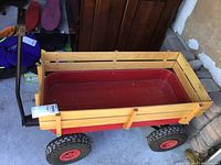 Full view of the metal wagon showing red tub, wooden side panels, tires and handle.