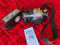 Pentax ME Super camera body with neck strap and Braun F110 flash unit lying on red quilted cloth.