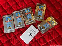 Five unopened foil packs of Upper Deck McDonald's collectible hockey cards with logos and hockey imagery, laid out on a red quilted background along with a maxsold lot tag.