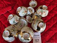 Top view of 8 upside down porcelain bowls showing floral patterns and red Chinese marks on the base with gold trim on edges.