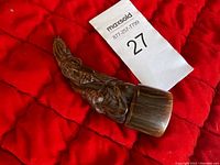 Top view showing detailed carving of figure in traditional attire on curved buffalo horn.
